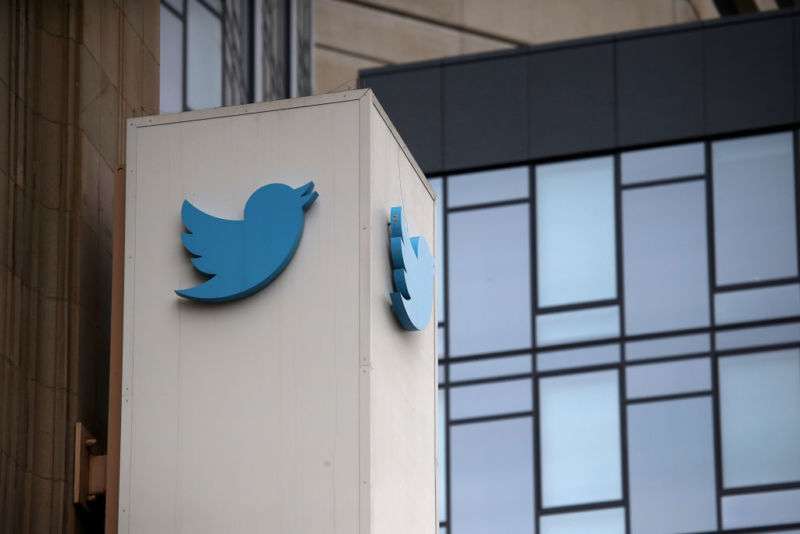 Exterior of glass-walled office building with Twitter logo on a column.