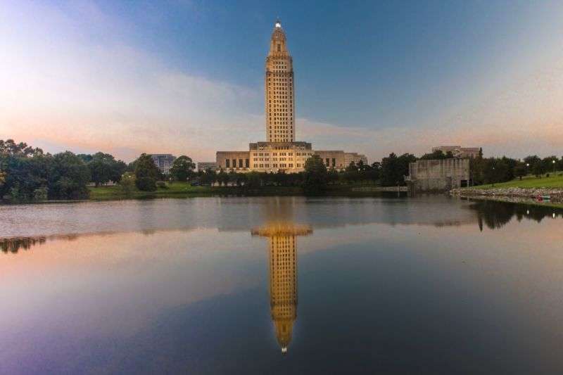 Building with tower overlooks its own reflection in lake.