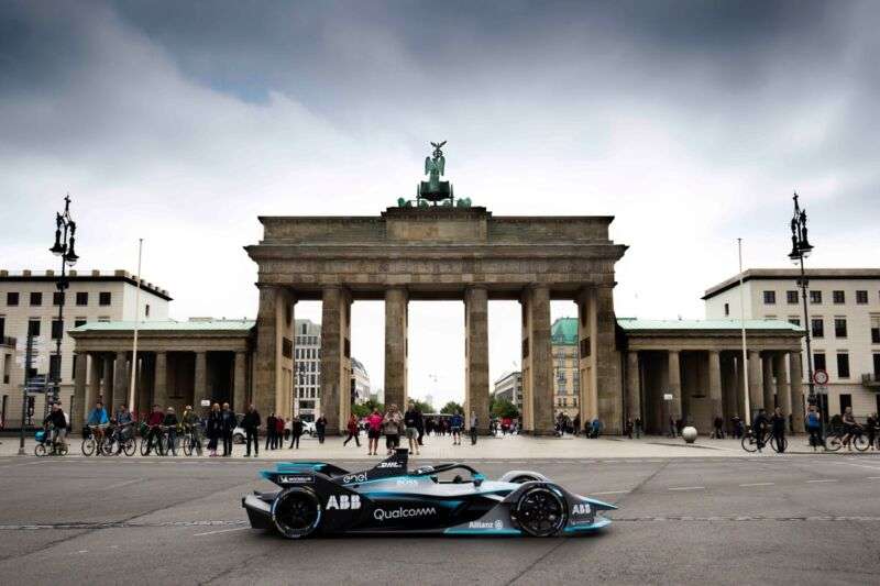 An electric race car on display in front of a German monument.